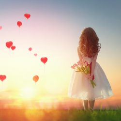 girl looking at red balloons