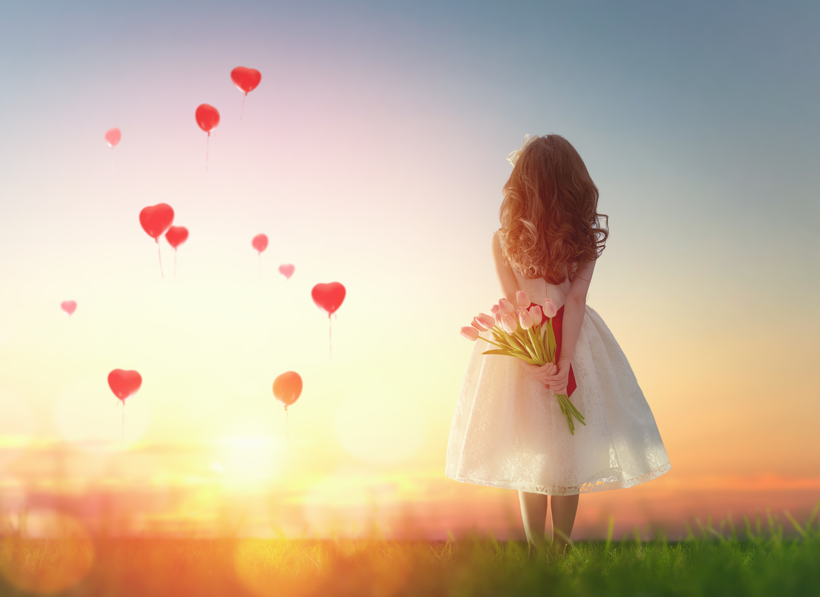 girl looking at red balloons